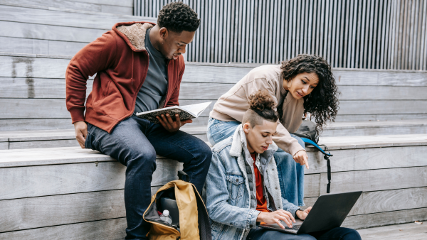 Studenten werken samen met laptop op schoolplein – IT-reparatie Onderwijs door MicroFix voorkomt uitval
